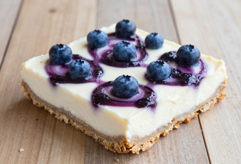 Keto blueberry cheesecake bars sliced and arranged in a baking dish, showing creamy filling and blueberry swirls.
