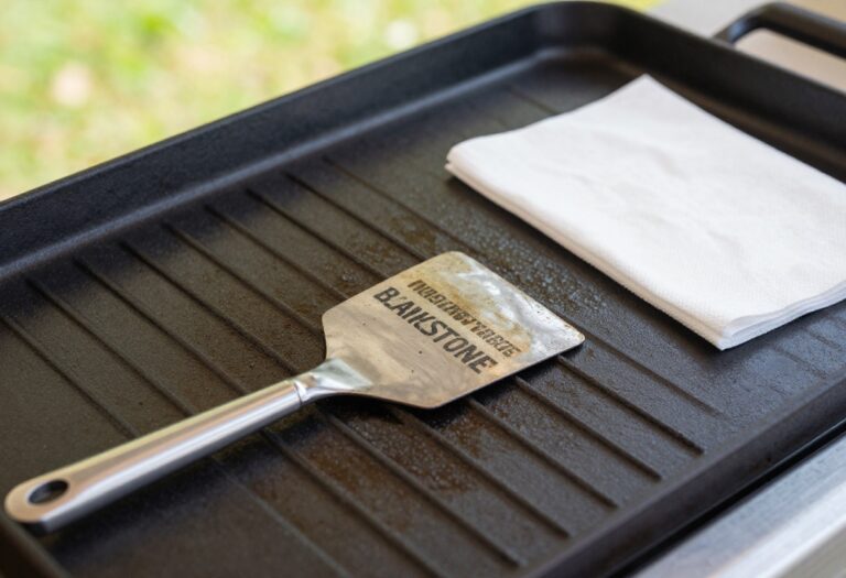 Clean Blackstone griddle surface with scraper and paper towel
