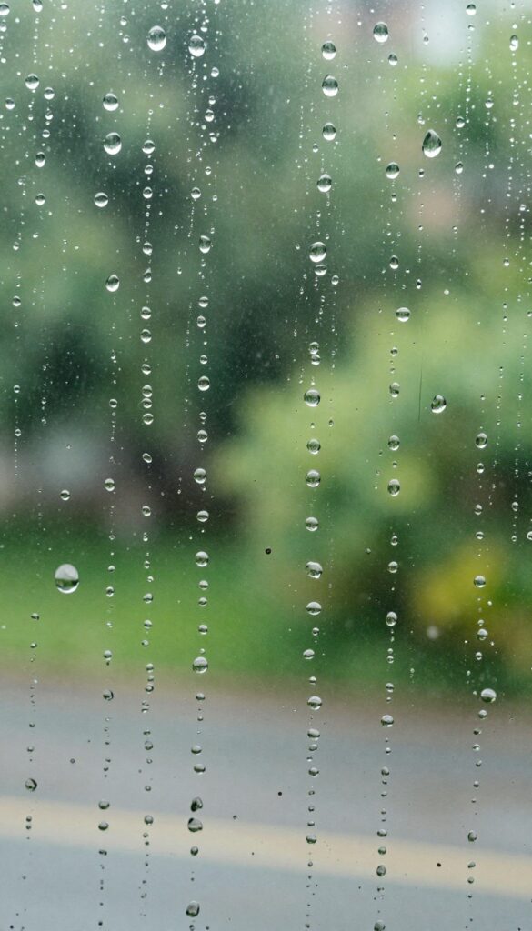 Raindrops beading on a treated exterior window with water repellency