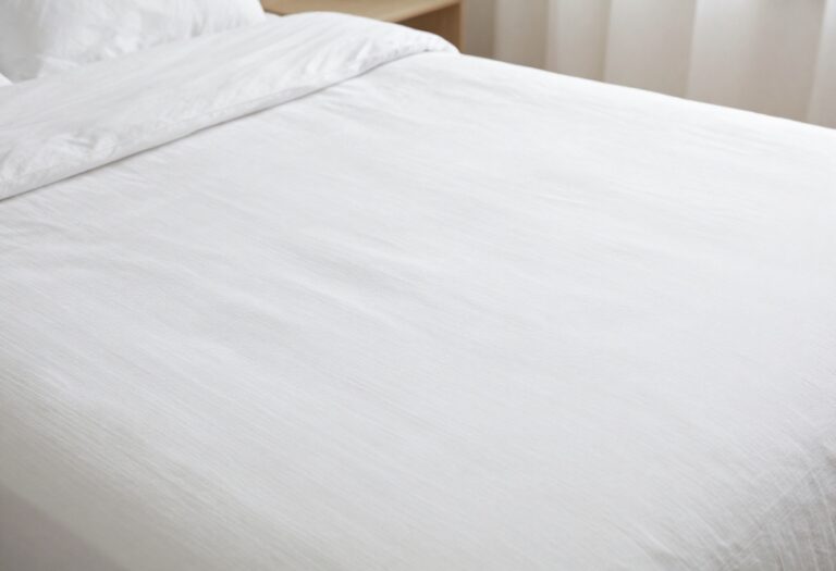 A clean white bed with fresh sheets and a spotless mattress in soft natural light