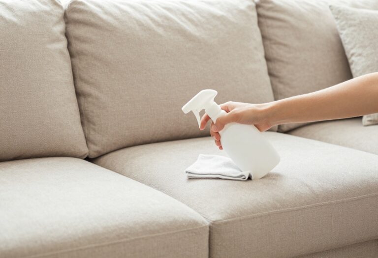 Person cleaning upholstery with a spray bottle and cloth