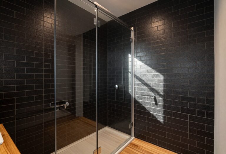 Modern shower with matte black subway tile, glass enclosure, and wood accents in a calm bathroom setting.